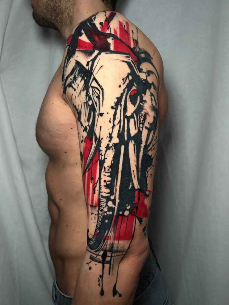 Tatuaggio trash polka di Lenny Fastidio, teschio di elefante su braccio e spalla