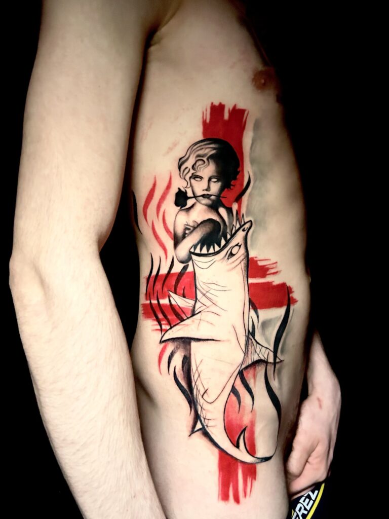 Tatuaggio trash polka di Lenny Fastidio, figura femminile e squalo sul costato