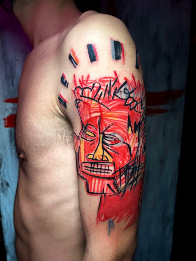 Tatuaggio di Lenny Fastidio, maschera rossa in stile tribale sul fianco