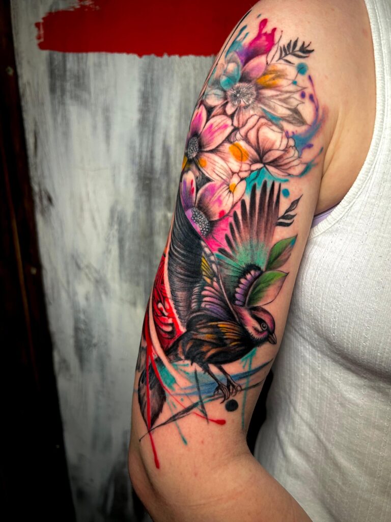 Tatuaggio di Lenny Fastidio, fiori e uccello sul braccio