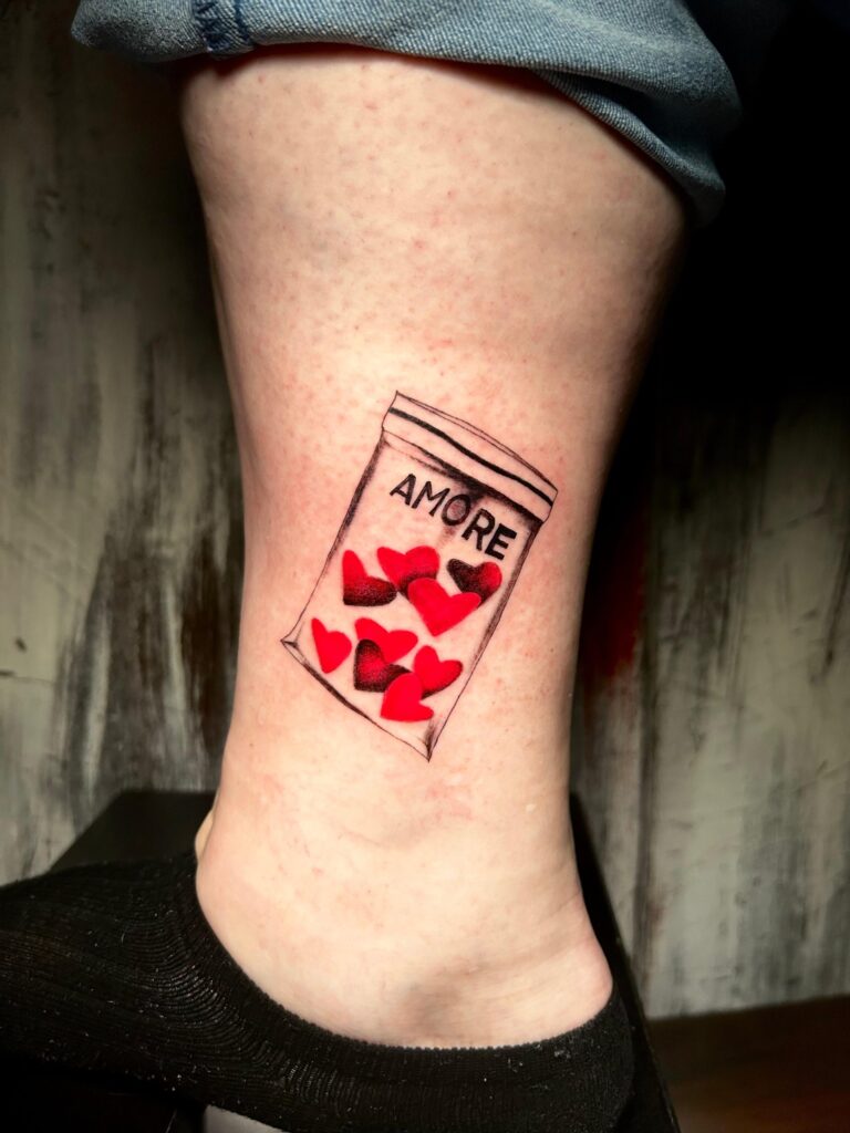 Tatuaggio di Lenny Fastidio, barattolo con cuori e scritta Amore sulla caviglia