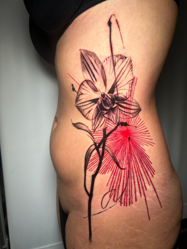 Tatuaggio di Lenny Fastidio, orchidea con raggi rossi sul fianco