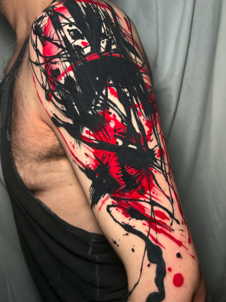 Tatuaggio di Lenny Fastidio, composizione astratta rossa e nera sul braccio
